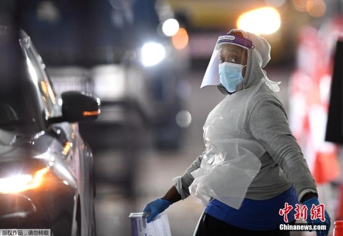 當(dāng)?shù)貢r(shí)間12月18日，英國政府公布的數(shù)據(jù)顯示，當(dāng)天英國新增奧密克戎毒株感染病例10059例。鑒于奧密克戎毒株感染病例激增，住院人數(shù)不斷上升，倫敦市長(zhǎng)宣布倫敦進(jìn)入“重大事故”狀態(tài)。圖為倫敦的一個(gè)免下車檢測(cè)中心，一名醫(yī)務(wù)工作者正準(zhǔn)備對(duì)司機(jī)進(jìn)行核酸檢測(cè)。