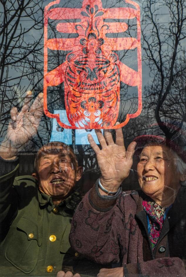 臘月里，霍州市師莊鄉(xiāng)馮南垣村村民師榮光(左)在災(zāi)后重建的新家里貼窗花。(霍州市委宣傳部供圖)