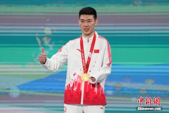 3月6日，梁景怡在延慶頒獎(jiǎng)廣場(chǎng)領(lǐng)獎(jiǎng)臺(tái)上豎起大拇指。當(dāng)日，在國(guó)家高山滑雪中心舉行的北京2022年冬殘奧會(huì)殘奧高山滑雪男子超級(jí)大回轉(zhuǎn)—站姿決賽中，中國(guó)選手梁景怡奪得冠軍。 <a target='_blank' href='/'>中新社</a>記者 楊華峰 攝