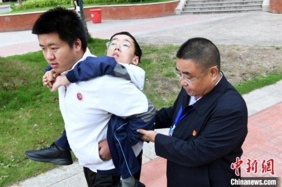 朱金祥背著鐘華強(qiáng)去教室上課的路上，也經(jīng)常碰到值班的校領(lǐng)導(dǎo)和老師前來(lái)搭把手。 卓忠偉 攝