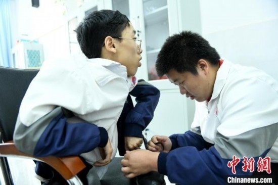 江西省南康中學(xué)北校區(qū)的高三學(xué)生朱金祥(右)正在給鐘華強(qiáng)(左)系好鞋帶。 卓忠偉 攝