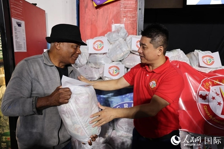 巴西中國浙江商會會長鄭俠茂向社區(qū)居民轉(zhuǎn)交捐贈物資。人民網(wǎng)記者 時元皓攝