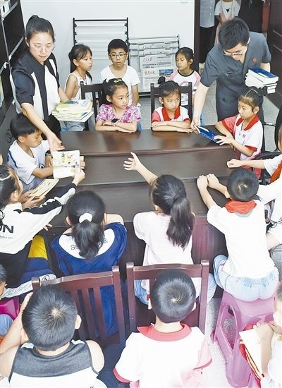  圖④：法院干警為留守兒童發(fā)放暑假讀物。