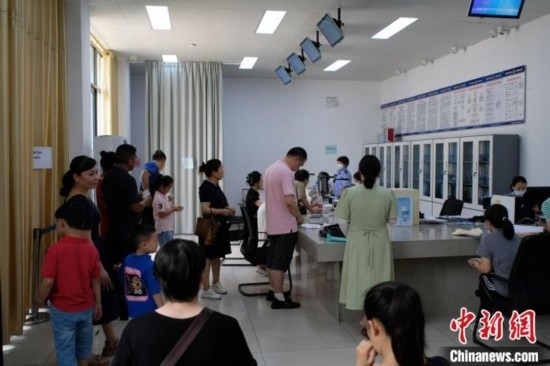 圖為在戶籍辦證廳內(nèi)排隊(duì)等待的家長和孩子。劉俊聰 攝