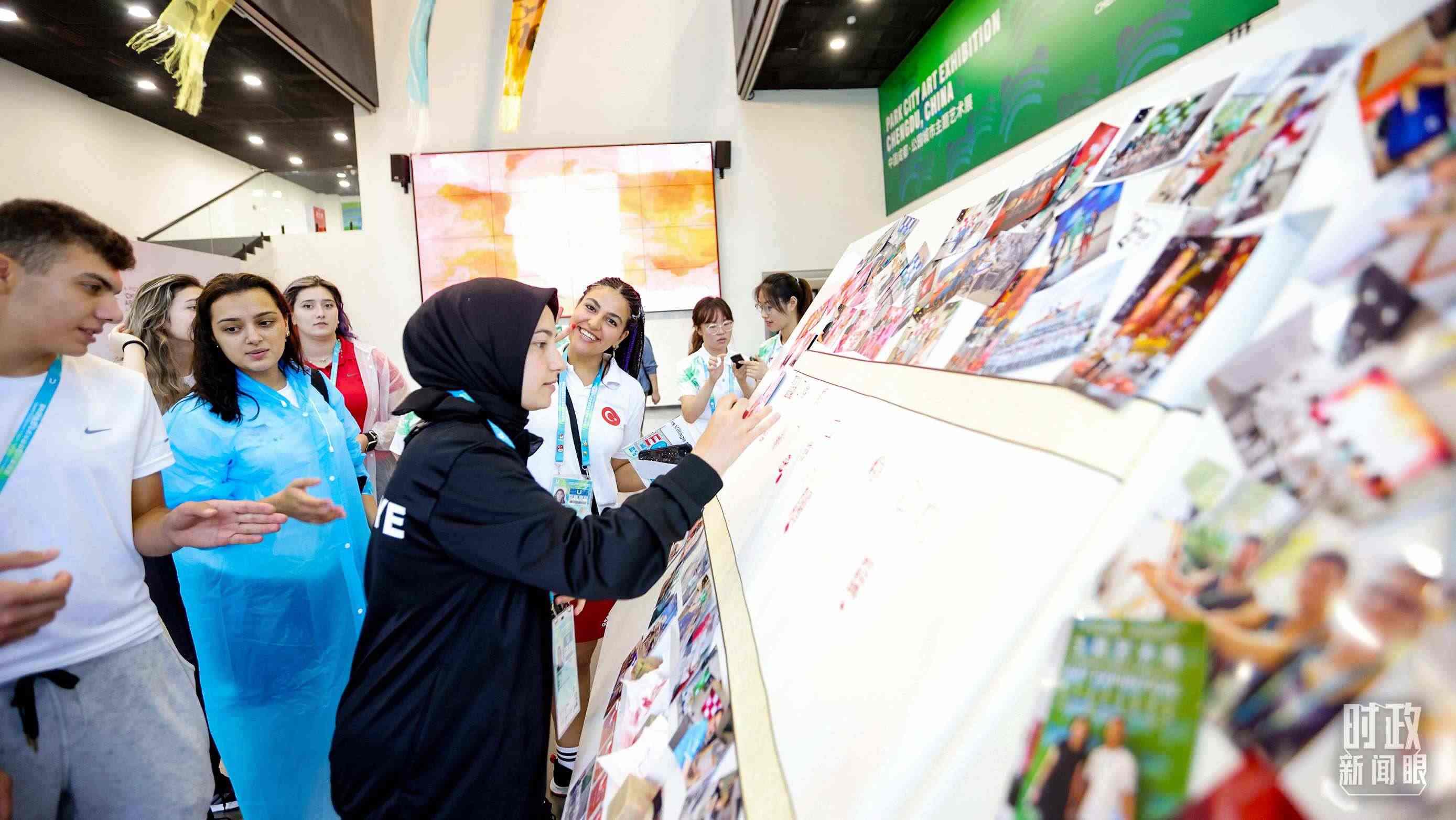 各國(guó)青年運(yùn)動(dòng)員正在參觀成都大運(yùn)村內(nèi)的“雪山下的公園城市，煙火里的幸福成都”主題藝術(shù)展。（總臺(tái)央視記者魏幫軍拍攝）