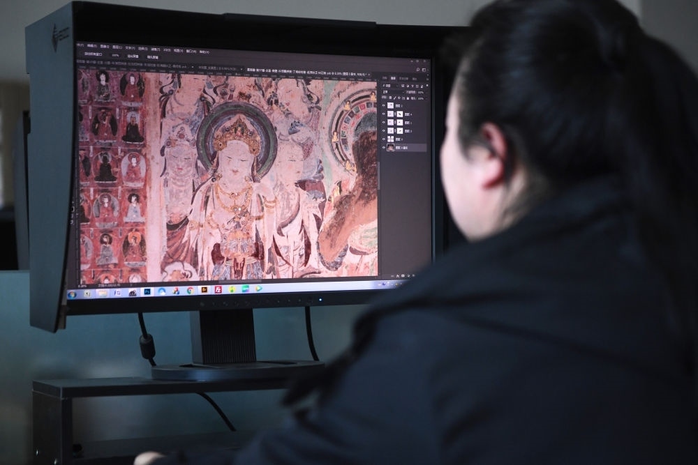 敦煌研究院文物數(shù)字化保護(hù)團(tuán)隊(duì)圖像處理人員年海麗在拼接壁畫圖像（2023年4月25日攝）。數(shù)字化探索為莫高窟的保護(hù)與傳承開(kāi)辟了全新路徑，數(shù)字技術(shù)讓敦煌文物走出洞窟，跨出國(guó)門，走向“永久保存、永續(xù)利用”。新華社記者 陳斌 攝