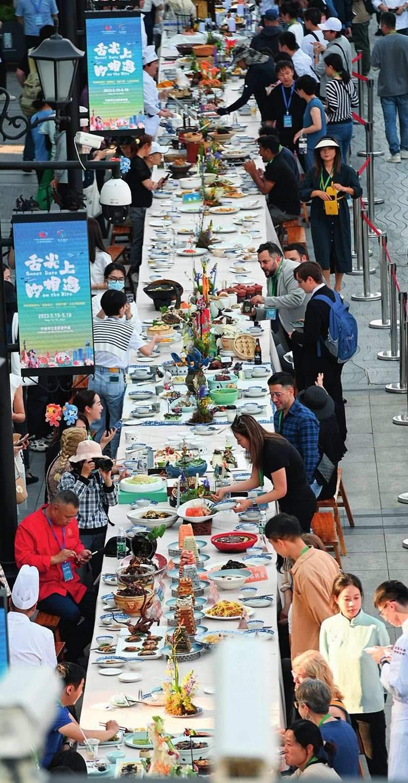 市民和游客在寧波舉辦的第三屆中國(guó)—中東歐國(guó)家博覽會(huì)暨國(guó)際消費(fèi)品博覽會(huì)上品嘗融合中國(guó)和中東歐美食的長(zhǎng)桌宴（2023年5月15日攝）。黃宗治攝/本刊