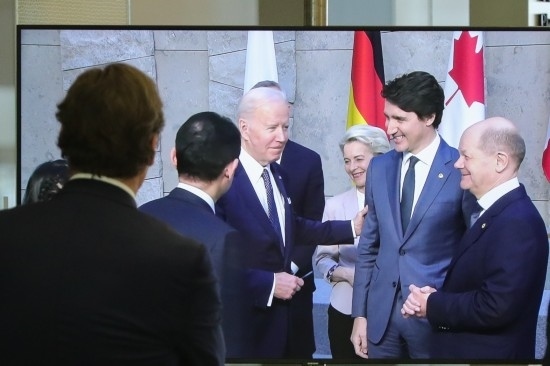 2022年3月24日，在比利時布魯塞爾的北約總部，一名男子觀看屏幕上美國總統(tǒng)拜登（右四）、歐盟委員會主席馮德萊恩（右三）、加拿大總理特魯多（右二）、德國總理朔爾茨（右一）出席七國集團峰會合影儀式的畫面。新華社記者鄭煥松攝