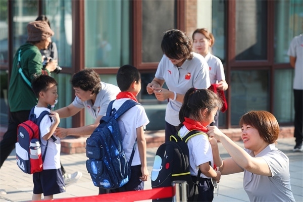 8月30日，雄安史家胡同小學學生體驗學校生活。老師為學生佩戴?；?。