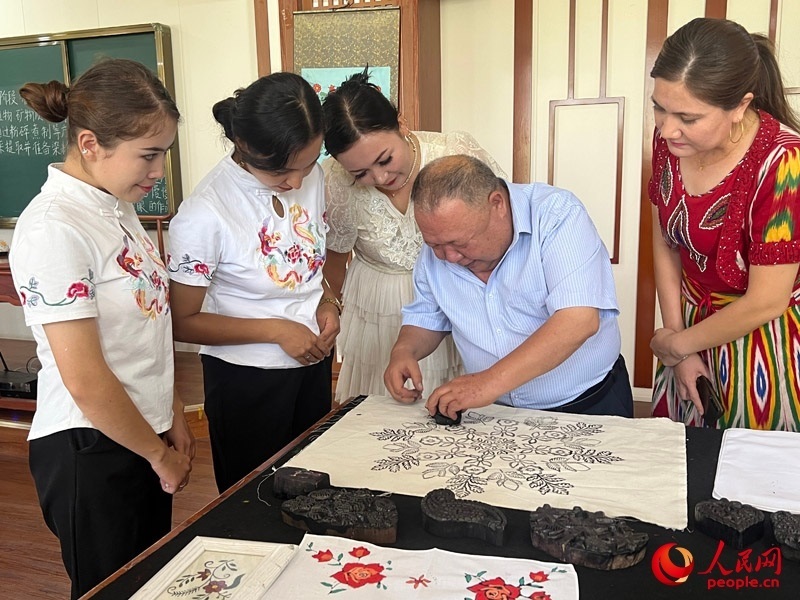 國家級非物質(zhì)文化遺產(chǎn)模戳印花布技藝傳承人吾吉阿西木?吾舒爾展示模戳印花布的制作過程。人民網(wǎng)記者 常雪梅攝
