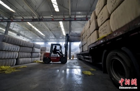 新疆喀什綜合保稅區(qū)，喀什啟路國際貿(mào)易有限公司的倉庫內(nèi)，工人正在裝載從塔吉克斯坦和烏茲別克斯坦進(jìn)口的棉花。劉新攝