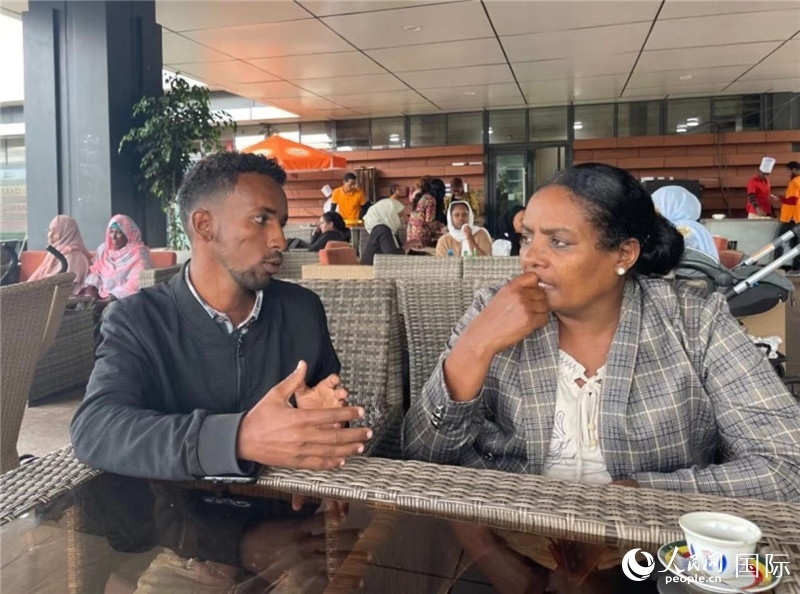 約漢斯（圖左）與德貝拉在友誼廣場咖啡廳交談。人民網(wǎng)記者 趙艷紅攝