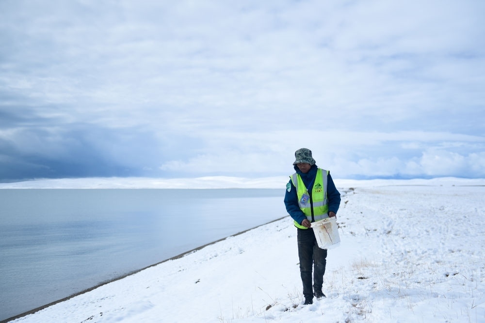 2021年10月20日，在青海省果洛藏族自治州瑪多縣扎陵湖鄉(xiāng)勒那村，三江源國(guó)家公園黃河源園區(qū)生態(tài)管護(hù)員在扎陵湖邊撿拾垃圾。新華社記者 張龍 攝