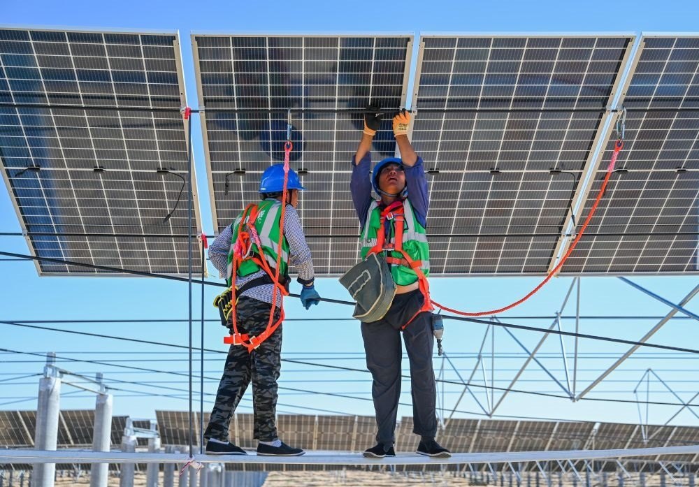 2023年7月22日，工人在位于內(nèi)蒙古杭錦旗庫布其沙漠億利生態(tài)示范區(qū)的蒙西基地庫布其200萬千瓦光伏治沙項(xiàng)目工地安裝光伏板。新華社記者 劉磊 攝