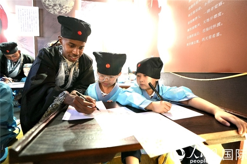 圖為選手與同學(xué)們一起寫(xiě)書(shū)法。人民網(wǎng) 盧鵬宇攝