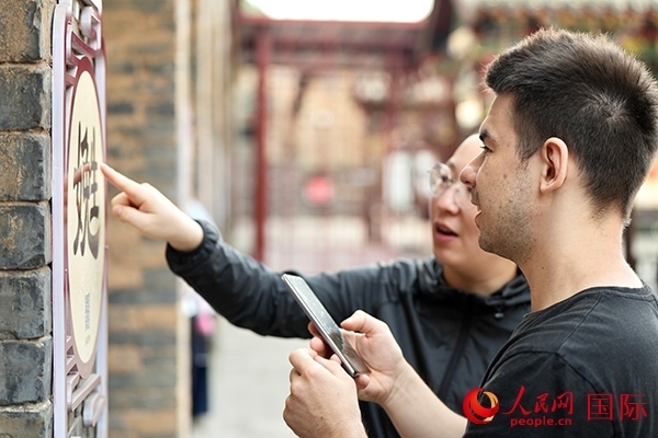 選手安德烈（俄羅斯）在老師指導(dǎo)下學(xué)習(xí)墻壁上張貼的生僻字。人民網(wǎng) 盧鵬宇攝