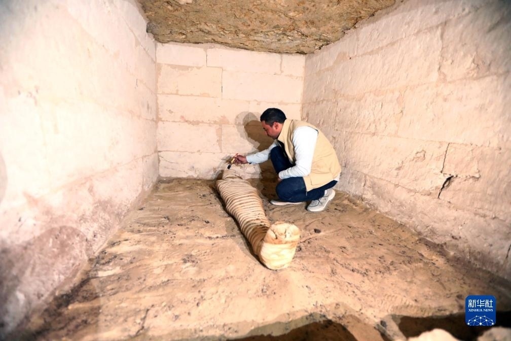 10月15日，在埃及明亞省考古現(xiàn)場，考古人員清理一座石鑿墓中的木乃伊。新華社發(fā)（艾哈邁德·戈馬攝）