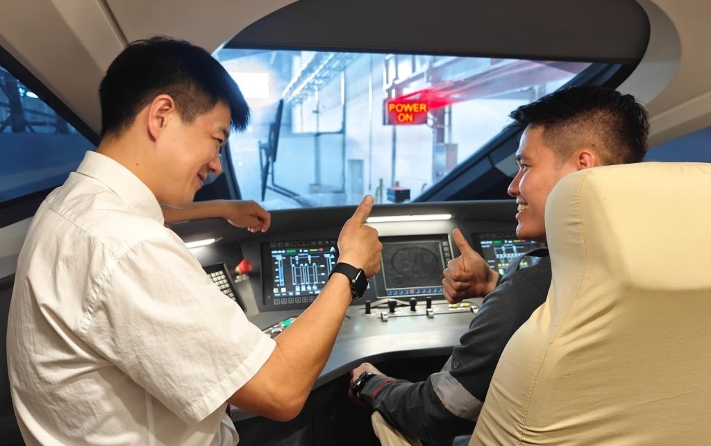 8月25日，在印度尼西亞萬隆的雅萬高鐵德卡魯爾動車所內(nèi)，中國師傅穆振（左）在向印尼火車司機(jī)塞蒂亞萬講解動車組出庫前的上電作業(yè)。