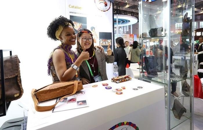 11月6日，一位參觀者（右）在第六屆進博會國家展南非展臺試戴傳統(tǒng)首飾。