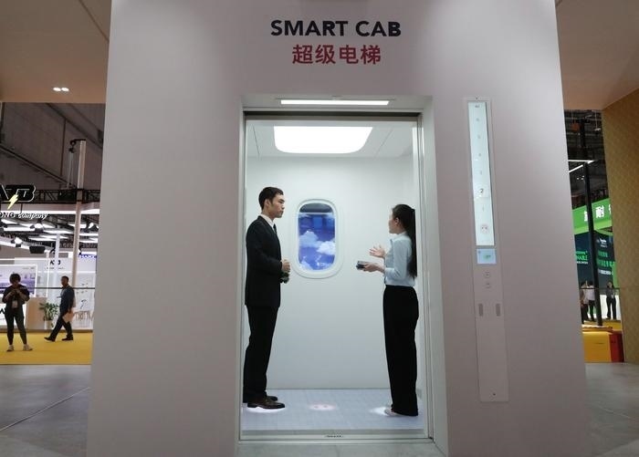 11月5日，工作人員（右）在第六屆進博會上向參觀者介紹奧的斯公司全新推出的超級電梯。