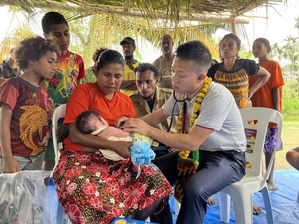 2023年8月5日，在巴布亞新幾內(nèi)亞中央省的一個村莊里，第12批援巴新中國醫(yī)療隊副隊長、新生兒科副主任醫(yī)師劉振球為嬰兒泰樂聽診檢查。泰樂出生時患有重癥，一度生命垂危，經(jīng)過劉振球與當(dāng)?shù)蒯t(yī)護(hù)人員的救治最終痊愈。從2002年起，中國連續(xù)向巴新派出12批醫(yī)療隊，為提高巴新醫(yī)療衛(wèi)生水平作出積極貢獻(xiàn)。