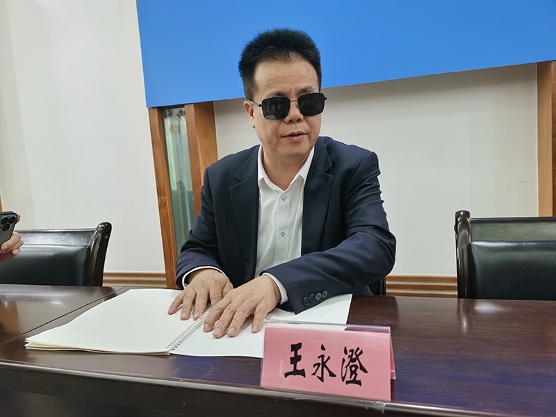 全國(guó)人大代表王永澄正在閱讀盲文版代表建議答復(fù)。本報(bào)記者 張 璁?dāng)z