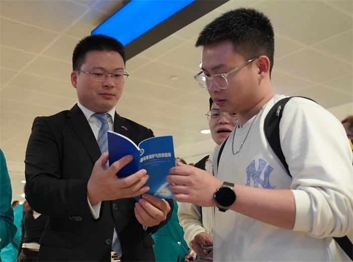 工作人員（左一）在發(fā)放《中國領(lǐng)事保護與協(xié)助指南》。 中國駐迪拜總領(lǐng)事館供圖