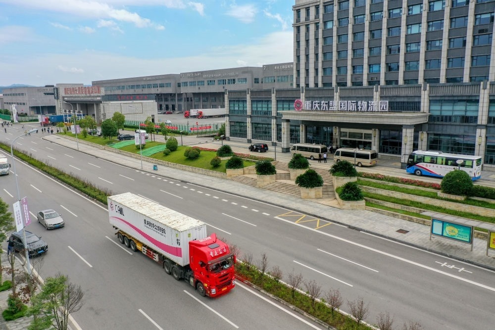 2023年10月11日，滿載筆記本電腦配件、發(fā)電機(jī)組件等產(chǎn)品的西部陸海新通道跨境公路班車從重慶南彭公路保稅物流中心駛出，將途經(jīng)廣西憑祥，直達(dá)越南（無(wú)人機(jī)照片）。新華社記者 黃偉 攝