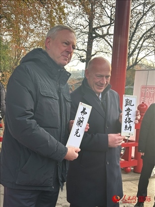 柏林市長韋格納（右）、動物園監(jiān)事會主席布魯克曼（左）手持中國文化中心工作人員現(xiàn)場手書的中文名字。人民網(wǎng)記者 徐馨攝