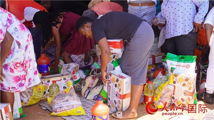 當(dāng)?shù)厣鐓^(qū)家庭領(lǐng)取物資。人民網(wǎng) 張茜攝