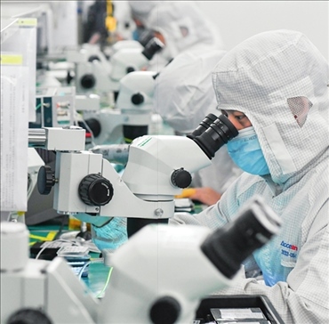 在位于武漢中國光谷的光電器件研發(fā)制造商——武漢光迅科技股份有限公司生產(chǎn)車間內(nèi)，技術(shù)人員在光模塊生產(chǎn)線作業(yè)（2023年4月11日攝）。程敏攝/本刊