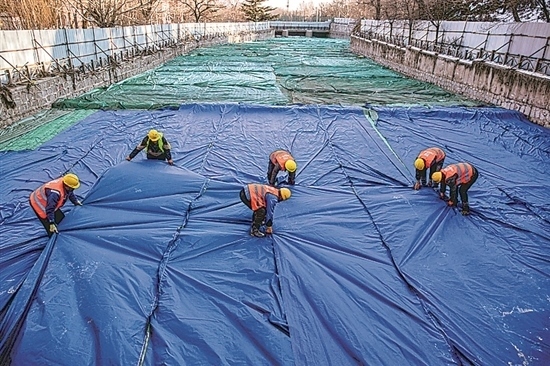 1月3日，房山區(qū)東風(fēng)街道，工人正在修復(fù)的河道內(nèi)給混凝土鋪設(shè)保溫布。