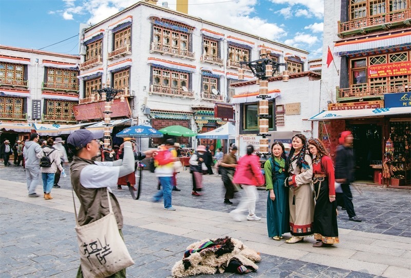 千年八廓街，見證民族團(tuán)結(jié)。2021年7月，習(xí)近平總書記來(lái)到位于西藏拉薩老城區(qū)的八廓街，感慨地說(shuō)：“千年八廓街，是我們各民族建起來(lái)的八廓街。各民族文化在這里交流交往交融，我們中華民族的大家庭在這里其樂(lè)融融?！眻D為2023年6月13日，游客身著藏裝在八廓街拍照留念。 新華社記者 姜帆/攝