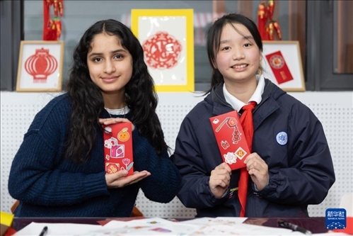 1月28日，美國(guó)馬斯卡廷中學(xué)學(xué)生（左）和復(fù)旦大學(xué)第二附屬學(xué)校學(xué)生展示互相送出的寫(xiě)有寄語(yǔ)祝福的紅包。 新華社記者 王翔 攝