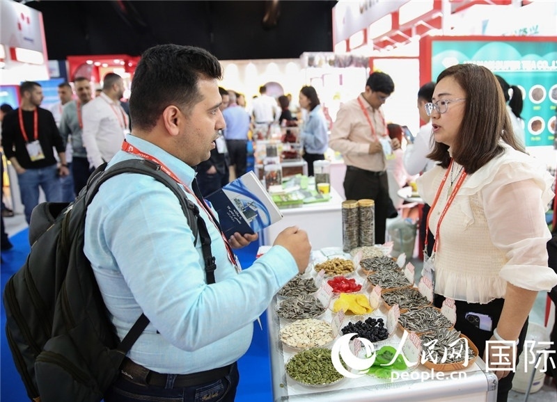 圖為一家中國干果參展企業(yè)代表與采購商洽談。人民網(wǎng) 塔里克·易卜拉欣攝