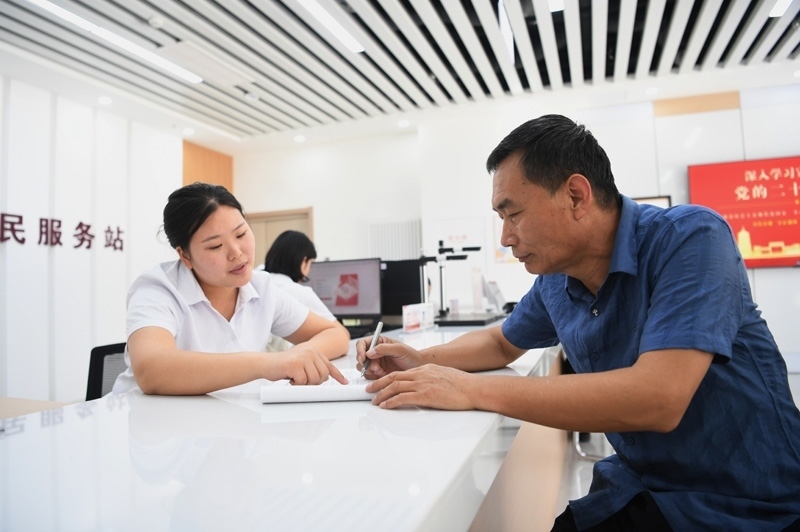2023年5月23日，河北雄安新區(qū)容東片區(qū)南文營(yíng)社區(qū)居民（右）在社區(qū)便民服務(wù)站辦理業(yè)務(wù)。