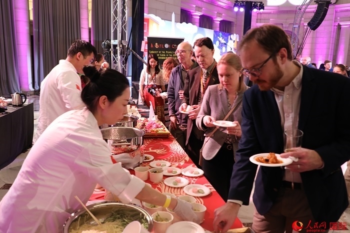 當?shù)貢r間3月7日晚，華盛頓聯(lián)合車站廣場舉行駐美使團“使館主廚挑戰(zhàn)賽”。圖為當?shù)孛癖娫谥袊古_前體驗中國美食。人民網(wǎng)記者 李志偉攝