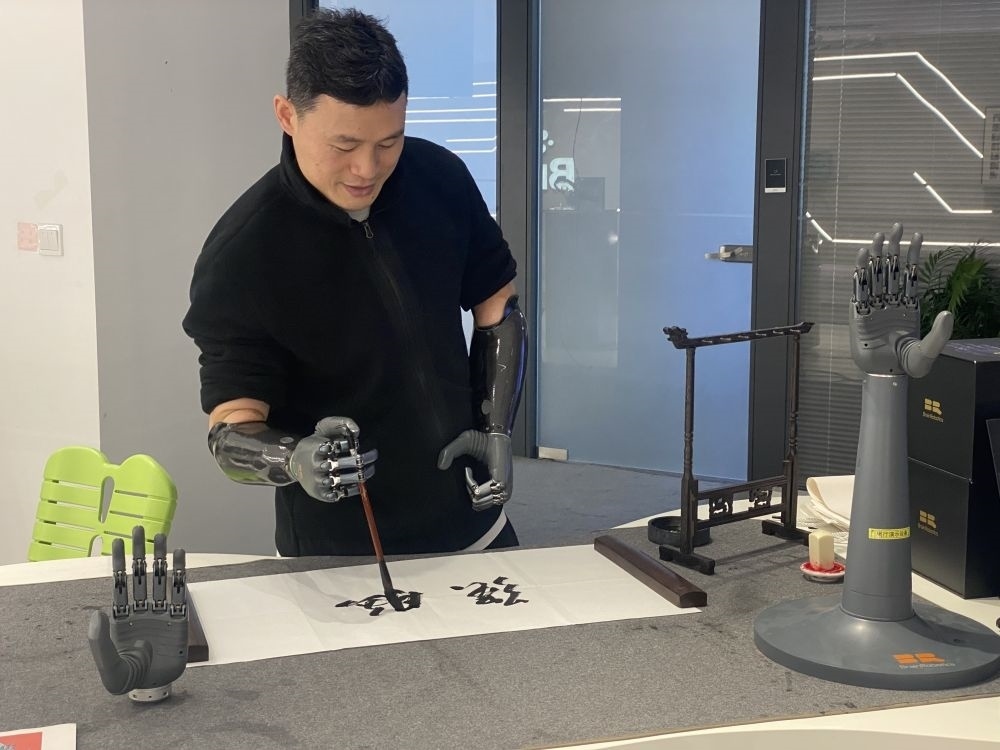 2024年3月29日，在浙江強(qiáng)腦科技有限公司展廳內(nèi)，失去雙手的產(chǎn)品體驗(yàn)官倪敏成依靠智能仿生手寫毛筆字。新華社記者 魏一駿 攝