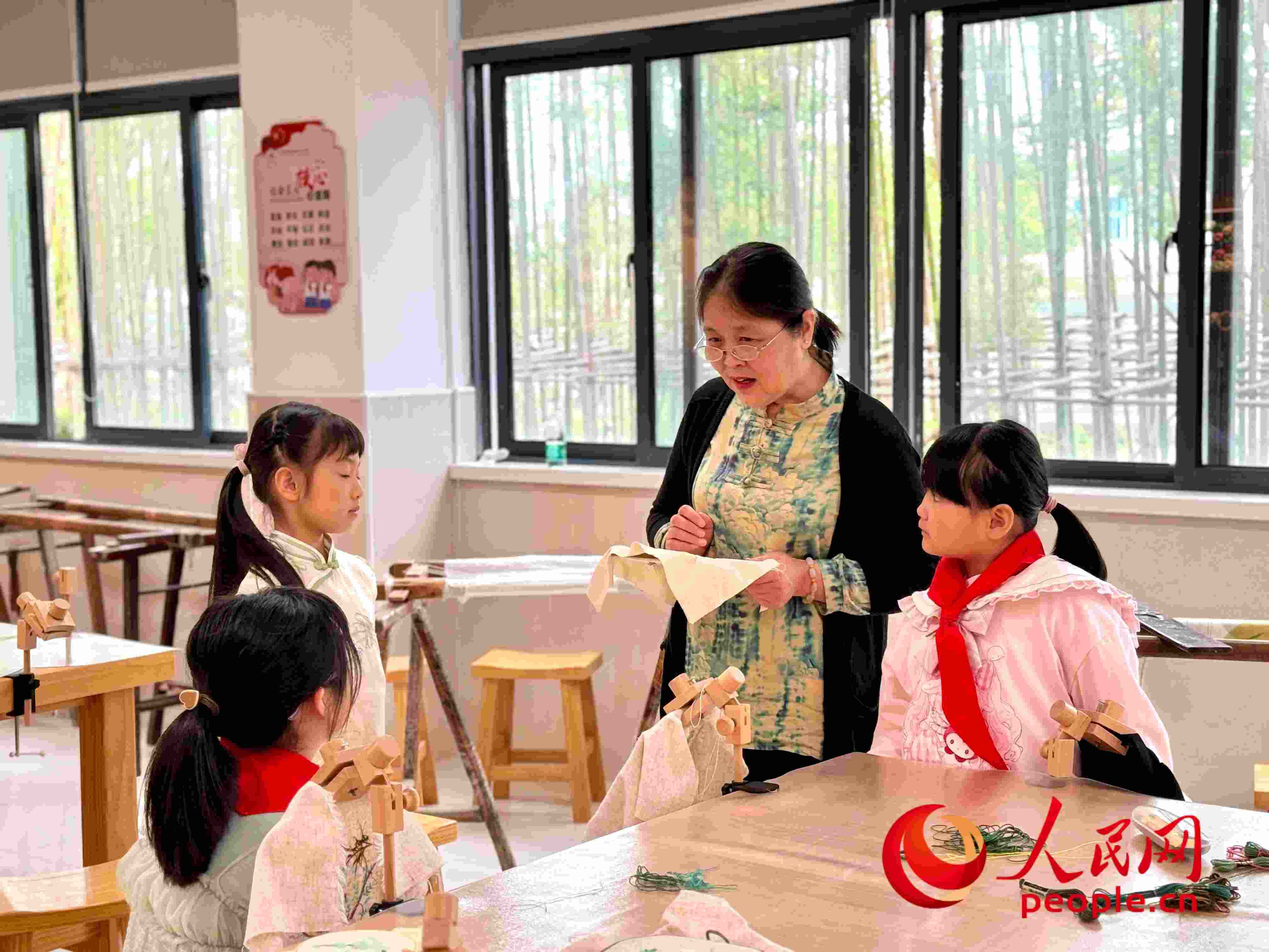 顧建珍（左三）在教孩子們刺繡知識。人民網(wǎng) 周靜圓攝