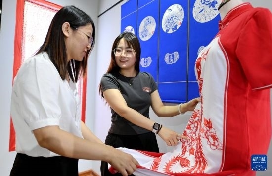 5月31日，在衡水市阜城縣一家剪紙工作室，游客在觀賞帶有剪紙元素的旗袍。