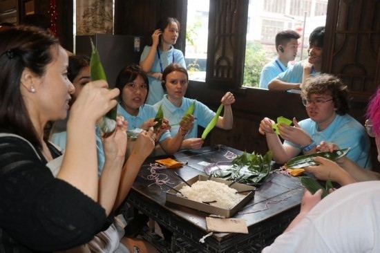 6月9日，美國(guó)青年代表在重慶永川松溉古鎮(zhèn)體驗(yàn)包粽子。新華社記者 周思宇 攝