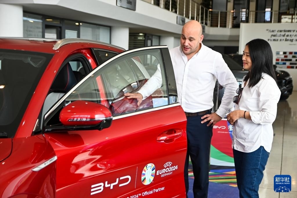 2024年5月29日，在馬耳他比爾基卡拉，馬耳他哈桑-扎米特汽車公司首席執(zhí)行官德古阿拉（左）介紹一輛比亞迪純電動(dòng)汽車。新華社發(fā)（喬納森·博格 攝）