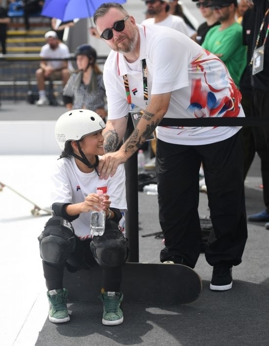 6月20日，鄭好好（左）在比賽間隙與教練互動，她在預賽中最佳成績?yōu)?2.60分。當日，巴黎奧運會資格系列賽布達佩斯站滑板女子碗池預賽在布達佩斯舉行。新華社記者 賀燦鈴 攝