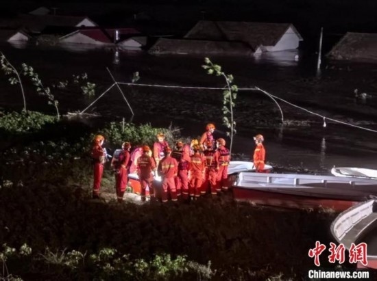  7月6日凌晨3時，在湖南岳陽華容縣團洲垸洞庭湖一線堤防，救援人員剛剛完成一次救援任務，遠處是被淹的民房。中新社記者 白祖偕 攝