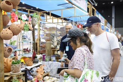 游客在蘭納博覽會特色展位上選購工藝品。人民網(wǎng)記者楊一攝