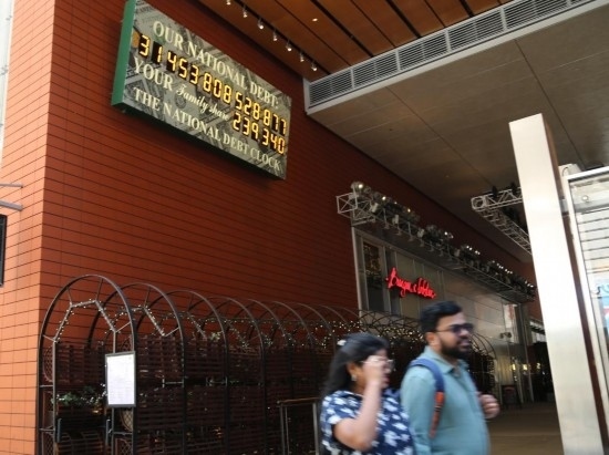 2023年5月29日，人們經(jīng)過美國紐約曼哈頓的“國債鐘”。“國債鐘”是一個(gè)大型計(jì)數(shù)器，它實(shí)時(shí)更新美國的公共債務(wù)總額，并顯示出每個(gè)美國家庭所要負(fù)擔(dān)的數(shù)額。 新華社記者劉亞南攝