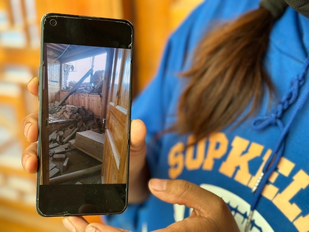 圖為7月17日拉毛東智在手機上找出地震后房屋受損的照片。新華社記者 張子琪 攝