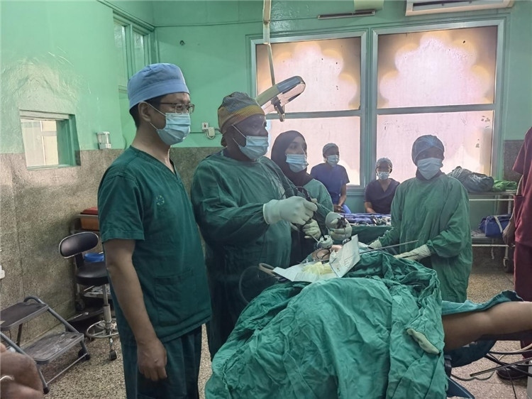隊長蔣國慶（左一）關注當?shù)蒯t(yī)生手術情況。中國援桑醫(yī)療隊供圖