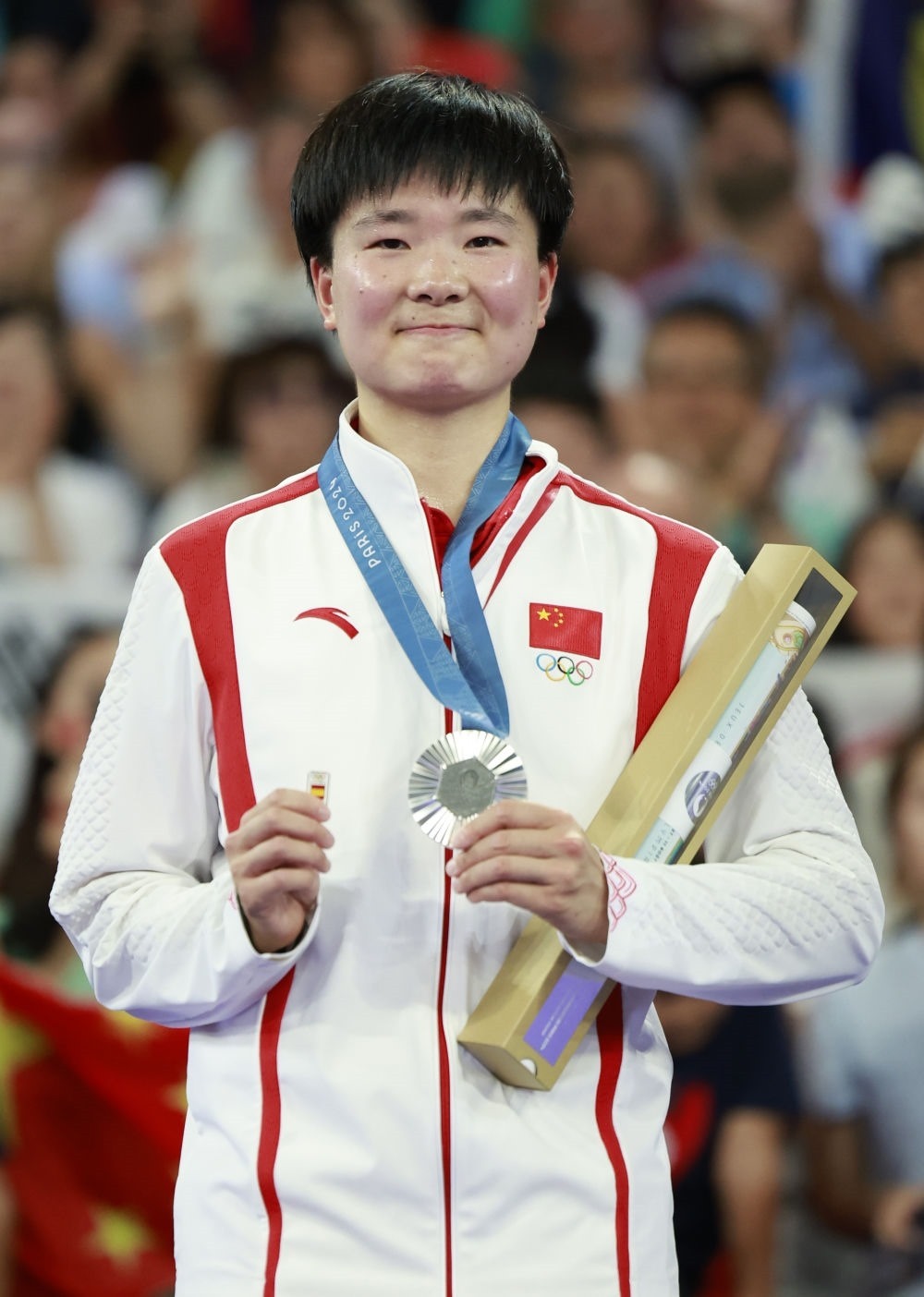 巴黎奧運會羽毛球女子單打亞軍、中國選手何冰嬌在頒獎儀式上一手握著銀牌，一手握著西班牙奧委會徽章（2024年8月5日攝）。新華社記者 任正來 攝