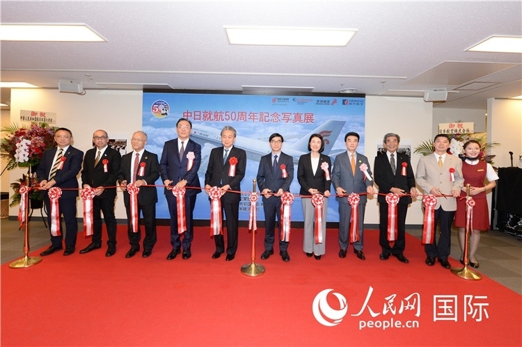 與會(huì)嘉賓共同為中日通航50周年紀(jì)念圖片展開幕剪彩。馮學(xué)敏攝